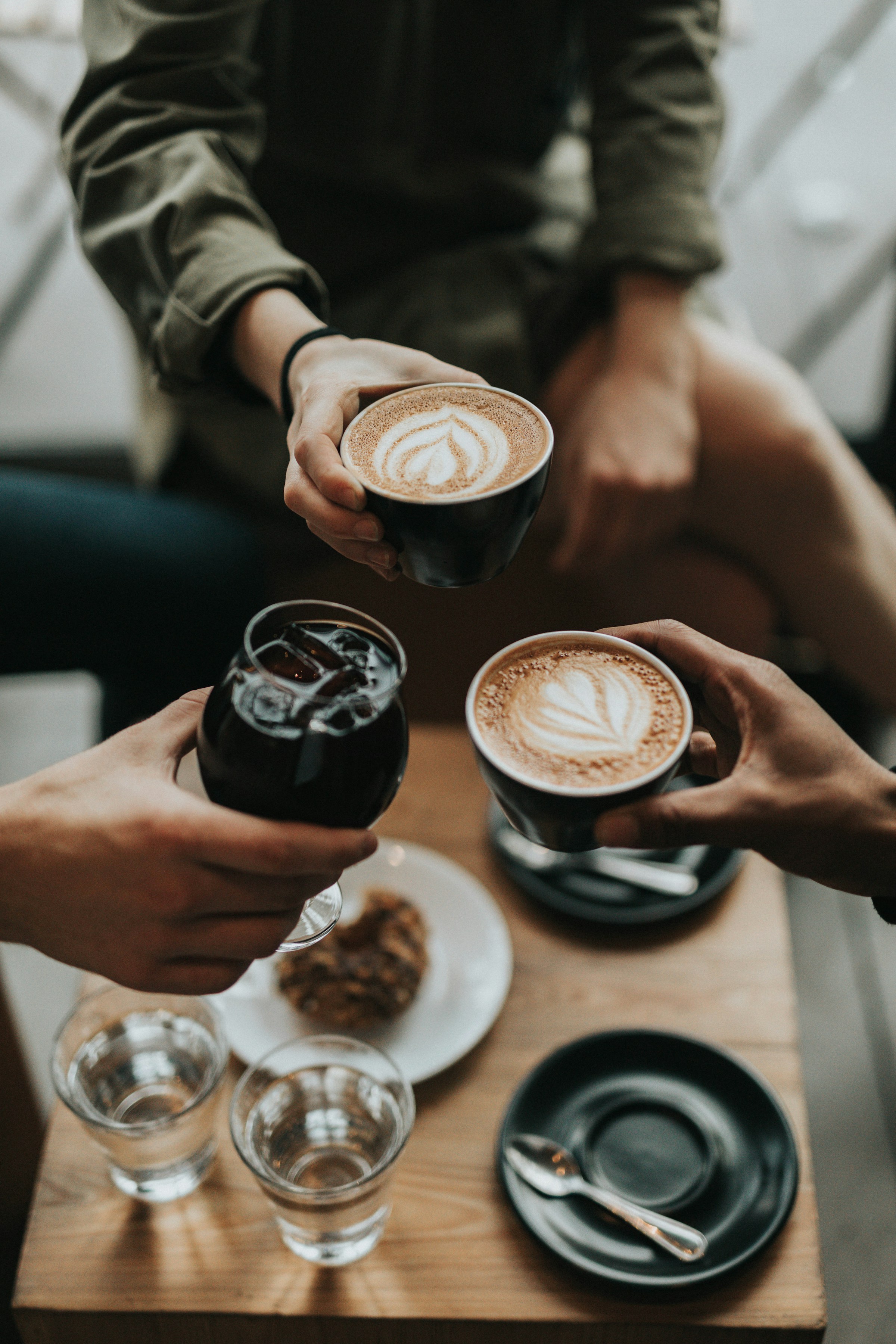 Three people holding their coffees together